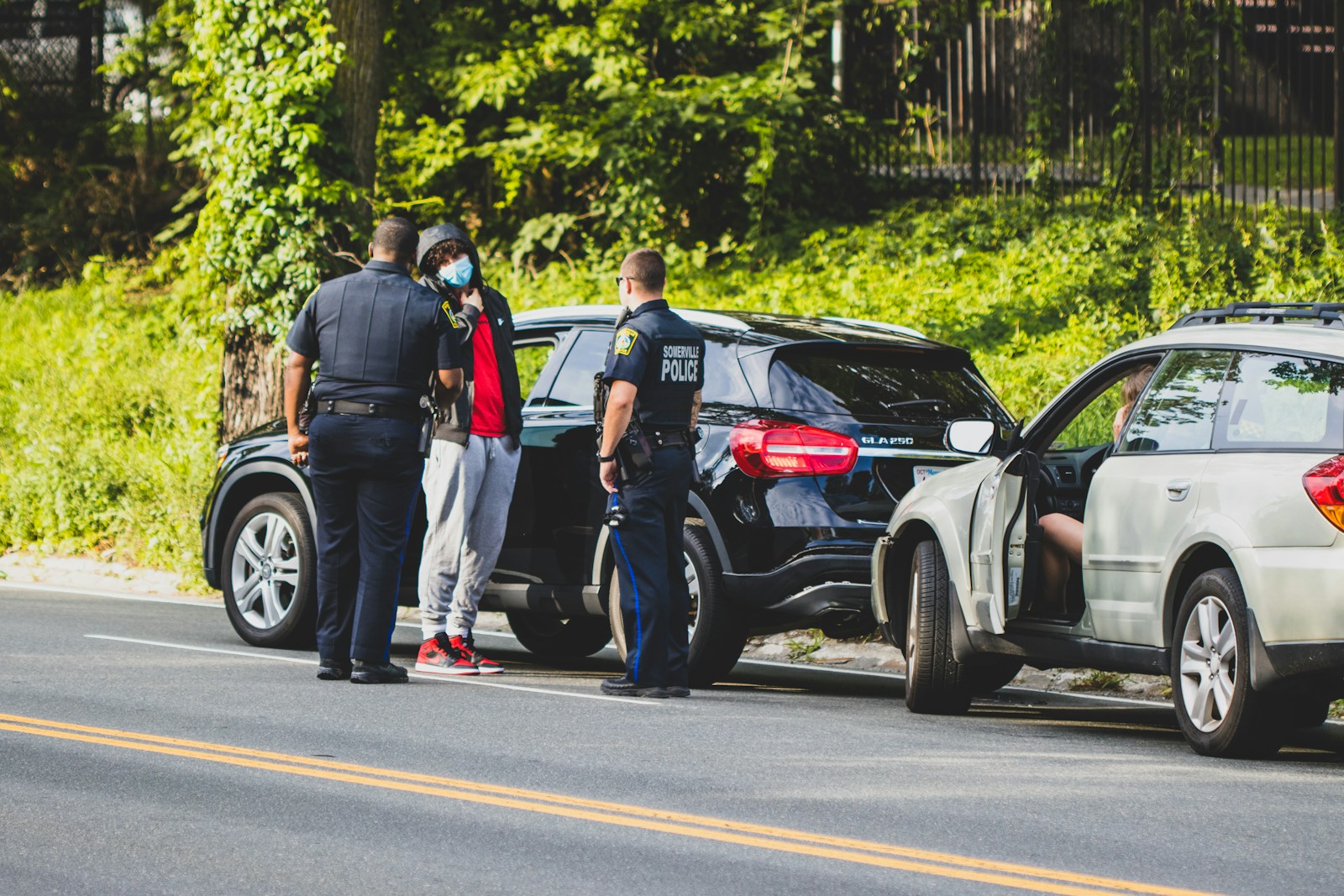 man in black t-shirt and black pants standing beside black suv during daytime auto
